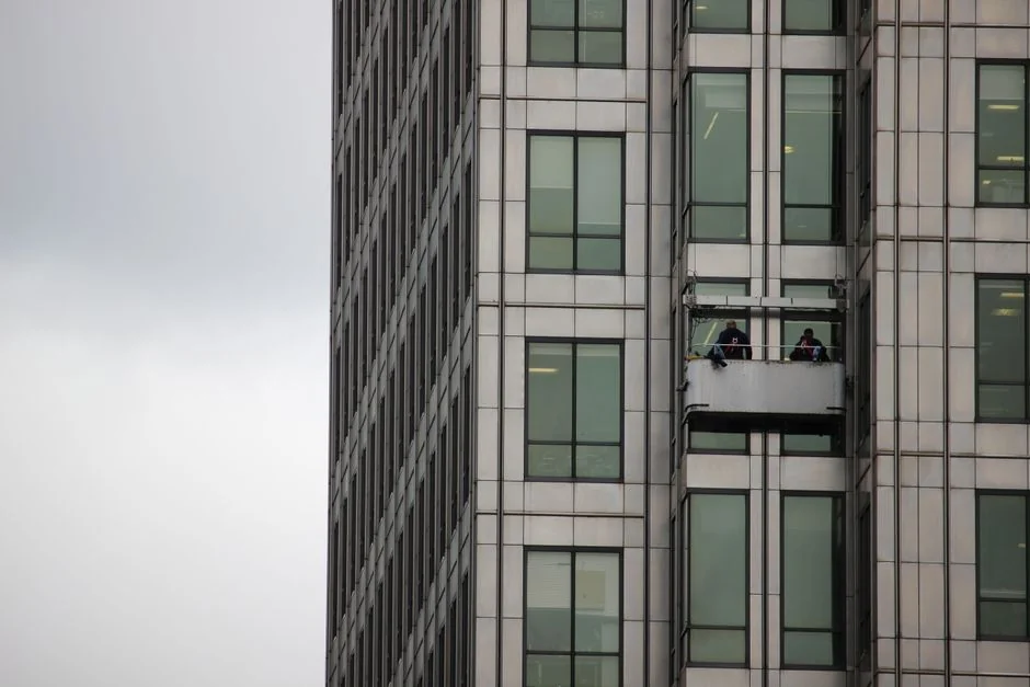 about-04 Two window cleaners using ropes on a modern skyscraper, showcasing urban professional maintenance.