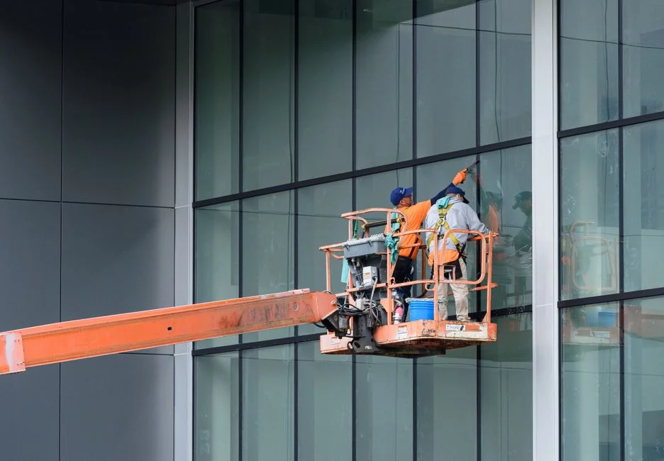 A male window cleaner washing the exterior glass roof from above with a tool during daylight.